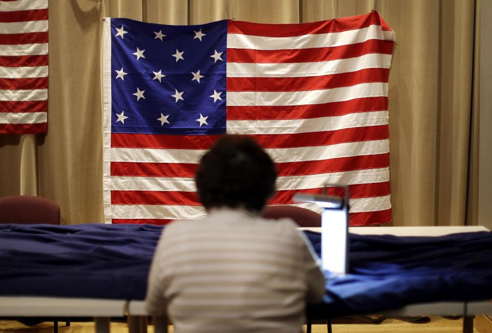 In this July 22, 2013 picture, with a model of the flag hanging above her, volunteer Joy Wiley sews a replica of the star-spangled banner in Baltimore as part of a project to commemorate the creation of the flag that inspired America’s national anthem. When finished, the replica will be about a quarter of the size of a basketball court. The project began July 4 in Baltimore, and it is expected to take volunteers six weeks to hand sew the estimated 150,000 stitches in the famous flag. (AP Photo/Patrick Semansky)