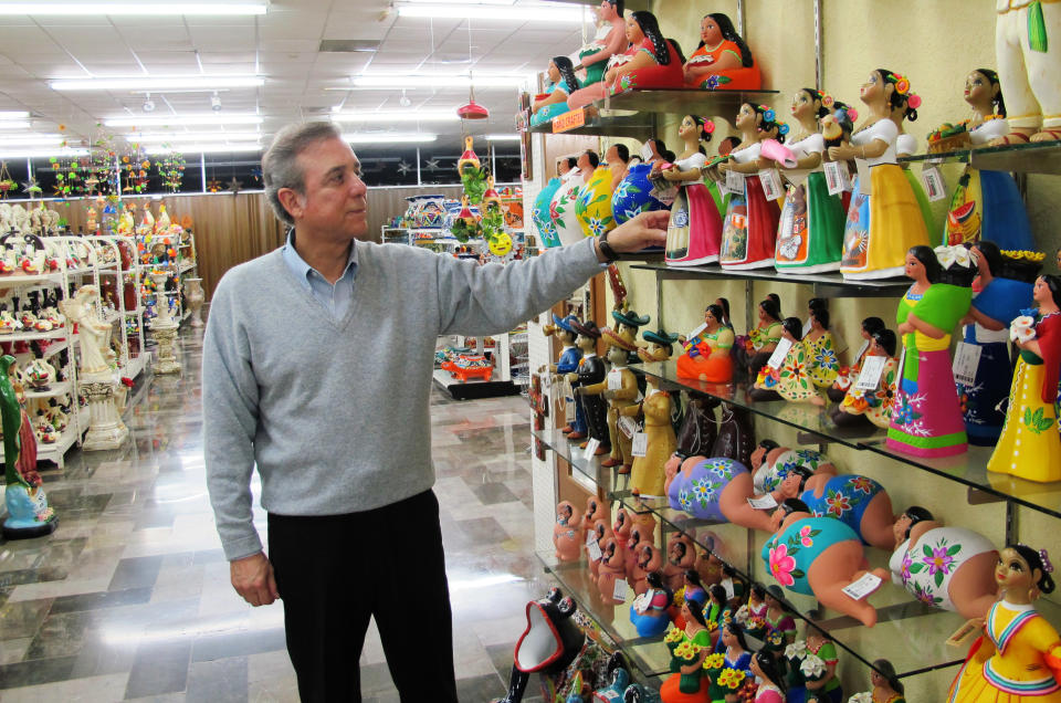 This Friday, Feb. 28, 2014 photo shows Ruben Garcia, manager and owner of Garcia's souvenir shop, checking prices on clay dolls in his store in Matamoros, Mexico. In the midst of a three-year increase in American tourism in Mexico, communities along the Rio Grande are trying to win back U.S. tourists and revitalize their tourism industry. (AP Photo/Olga Rodriguez)