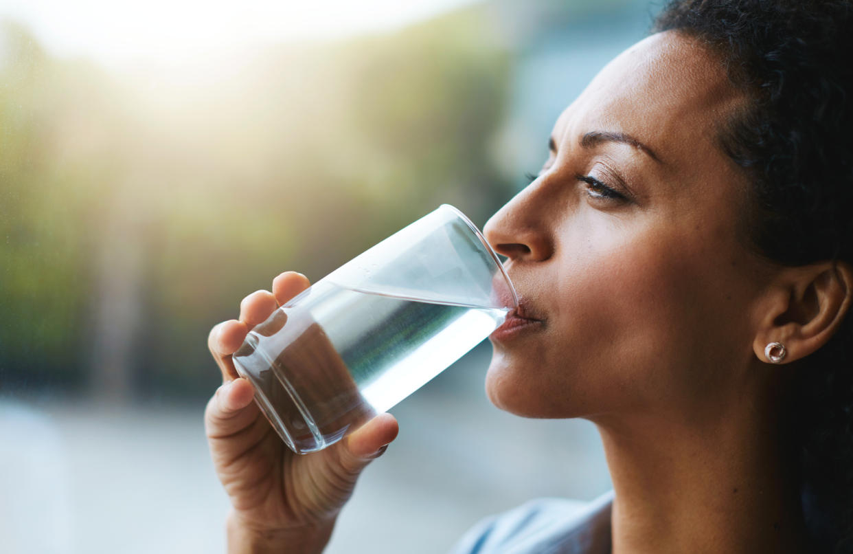 Woman drinking a glass of water. (Getty Images)