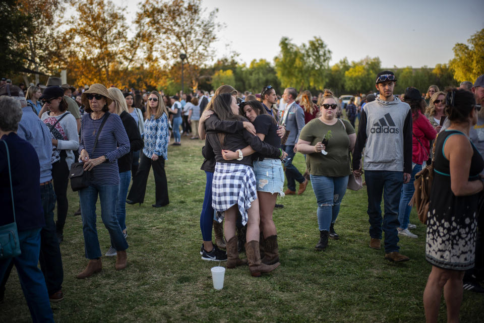 People comfort one another during the dedication of the Borderline Healing Garden at Conejo Creek Park in Thousand Oaks, Calif., Thursday, Nov. 7, 2019. The dedication marked the anniversary of a fatal mass shooting at a country-western bar a year earlier. (Hans Gutknecht/The Orange County Register via AP)