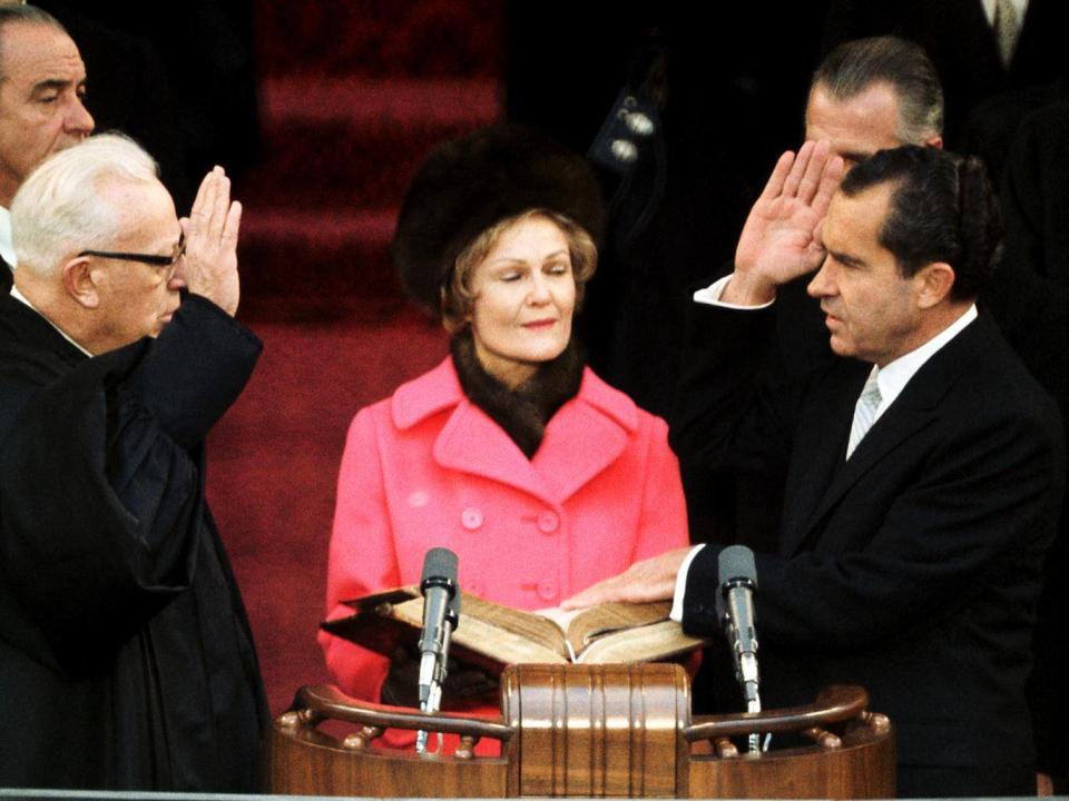 Chief Justice Earl Warren swears in the 37th president on 20 January 1969, as Nixon’s wife Pat looks on (Getty)