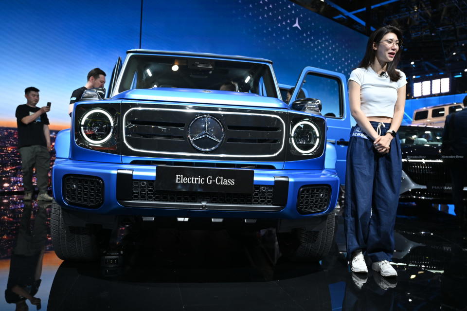 Eine Frau steht vor einer Mercedes G-Klasse auf der Automesse in China. Die "Auto China" gilt als wichtigste Messe der Automobilbranche in China. - Copyright: picture alliance/dpa | Johannes Neudecker