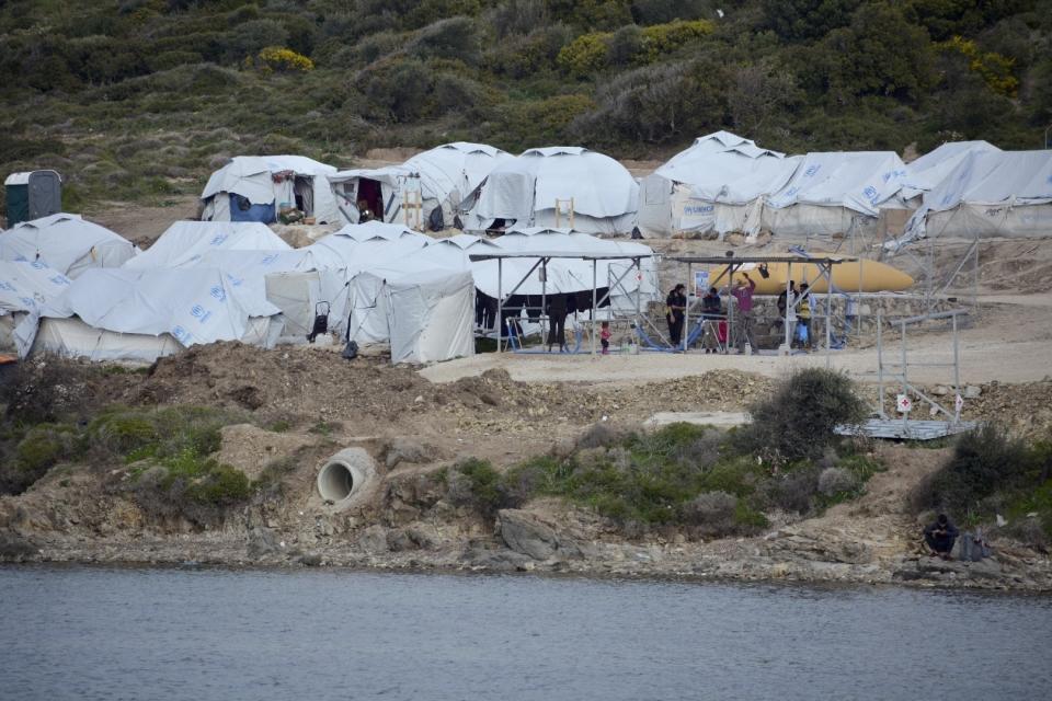 FILE - In this file photo dated Monday, March 29, 2021, migrants gather outside their tents a refugee camp, on the eastern Aegean island of Lesbos, Greece. Greek authorities on island of Lesbos said Tuesday July 20, 2021, they are drawing up a criminal case, including on charges of espionage, against 10 people, all foreign nationals, for allegedly helping migrants enter the country illegally. No suspects have been publicly identified. (AP Photo/Panagiotis Balaskas, FILE)