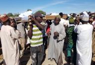 Men carry the bodies of people killed by militant attack, during a mass burial in Zabarmari