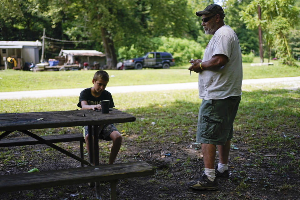 John Ross and his son David talk about their concerns for school reopening in the fall in light of the coronavirus pandemic and the way their limited internet access will hinder home instruction, in Beattyville, Ky., Wednesday, July 29, 2020. “They’re going to have their education,” the father of three said of his determination to get his children back to school after they struggled to do their work this spring over a spotty cellphone connection. (AP Photo/Bryan Woolston)