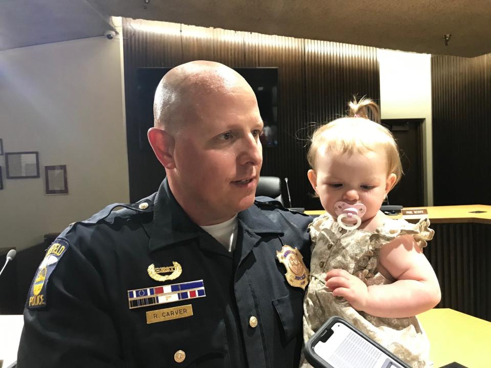 Mansfield police Capt. Randy Carver, holding  his granddaughter Everleigh, talks to media after his promotion ceremony Wednesday at Council Chambers.