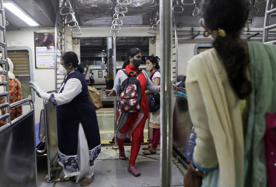 Women passengers enter a local train in Mumbai, India, Wednesday, Oct. 21, 2020. Indian railways has permitted women passengers to travel in local trains during non-peak hours beginning Wednesday, which otherwise has been running only for essential services. (AP Photo/Rajanish Kakade)