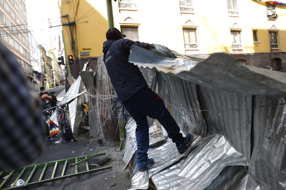 Supporters of former President Evo Morales bring down a barricade that was keeping them from reaching the presidential palace, during clashes with police in La Paz, Bolivia, Friday, Nov. 15, 2019. Morales stepped down on Sunday following nationwide protests over suspected vote-rigging in an Oct. 20 election in which he claimed to have won a fourth term in office. An Organization of American States audit of the vote found widespread irregularities. (AP Photo/Natacha Pisarenko)