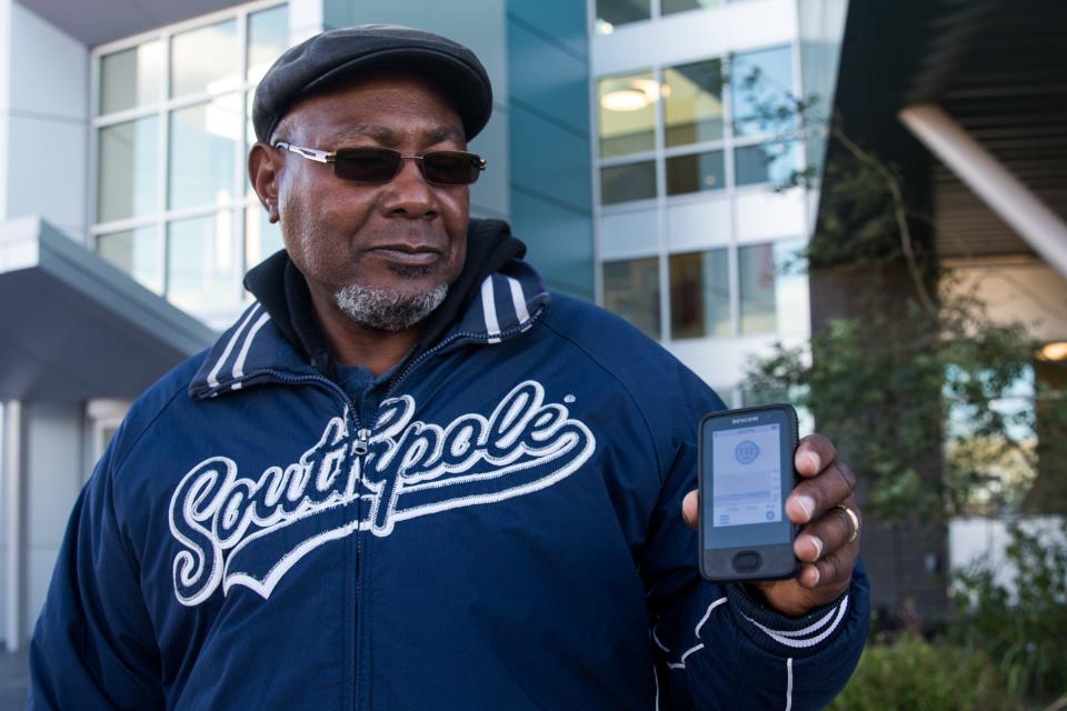 David Grigsby holds up the reader for his CGM outside a federally funded health clinic  in Tucson on February 17, 2022.