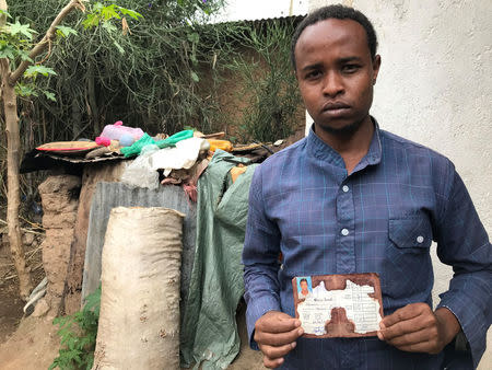 Abedir Jamal holds the identification card of his late brother Obsa Jemal, who was killed in anti-government protests, during a Reuters interview in Harar, Ethiopia July 22, 2018. REUTERS/Maggie Fick