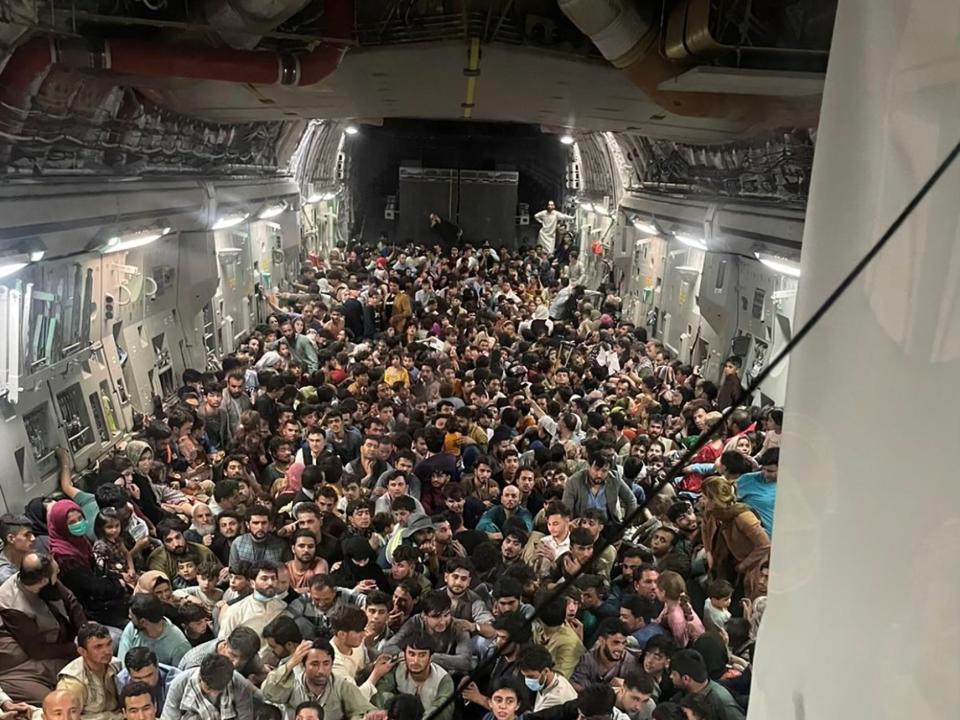 Hundreds of people sitting on the floor of a transport aircraft