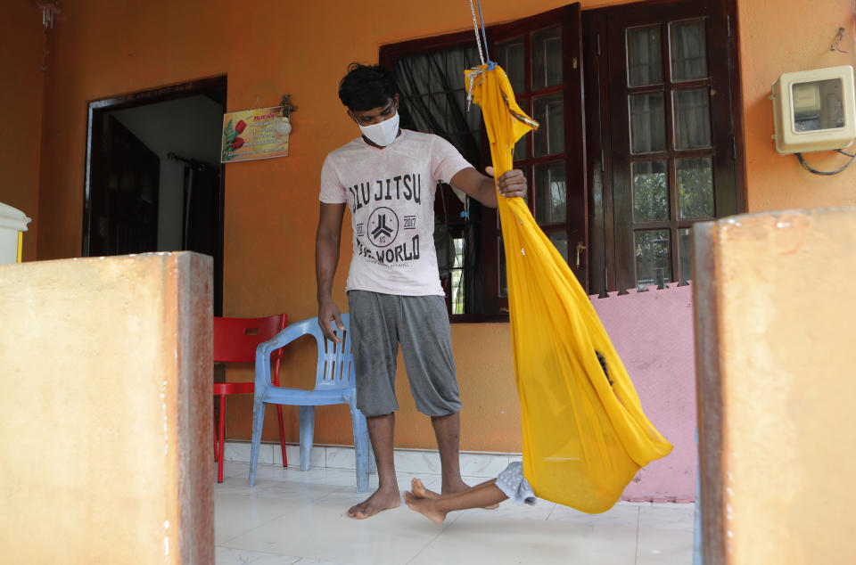 Sri Lankan auto rickshaw driver Prasad Dinesh, linked by Sri Lankan officials to nearly half the country's more than 2,600 coronavirus cases, pushes his daughter in a swing at their home in Ja-Ela, Sri Lanka, Wednesday, July 1, 2020. For months he’s been anonymous, but now Dinesh is trying to clear his name and shed some of the stigma of a heroin addiction at the root of his ordeal. Referring to him only as “Patient 206,” government officials lambasted Dinesh on TV and social media, blaming him for at least three clusters of cases, including about 900 navy sailors who were infected after an operation in Ja-Ela, a small town about 19 kilometers (12 miles) north of the capital, Colombo. Dinesh, however, says his drug addiction, which is considered a crime in Sri Lanka, makes him a convenient scapegoat. (AP Photo/Eranga Jayawardena)