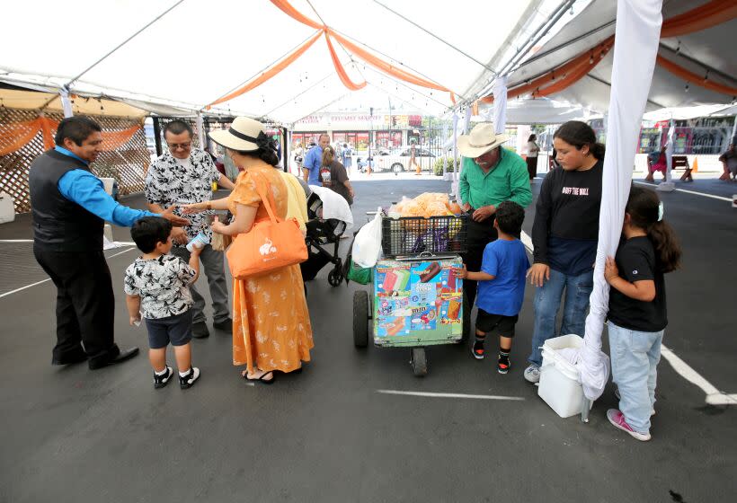 Ice cream vendor Jose Villa, 72 of L.A., is surrounded by customers after Sunday service at Iglesia Pentecostal Esmirna, in the Highland Park area of Los Angeles on Sunday, July 1, 2023. Villa, originally from Sinaloa, Mexico, has been selling ice cream for eight years after being laid off from a pizzeria. Villa has been in the United States since 1996 and continues working since he is not eligible to receive government financial benefits because of his legal status.