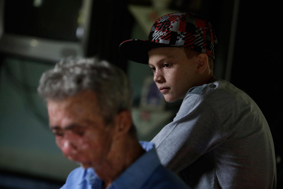 In this March 3, 2014 photo, Alisson Wendel Machado Freire, 11, listens to his grandfather Jose Claudio Machado, 77, play the guitar inside their home in the Araras community of Brazil's Goias state. Both of them suffer from a rare inherited skin disease known as xeroderma pigmentosum, or "XP."(AP Photo/Eraldo Peres)