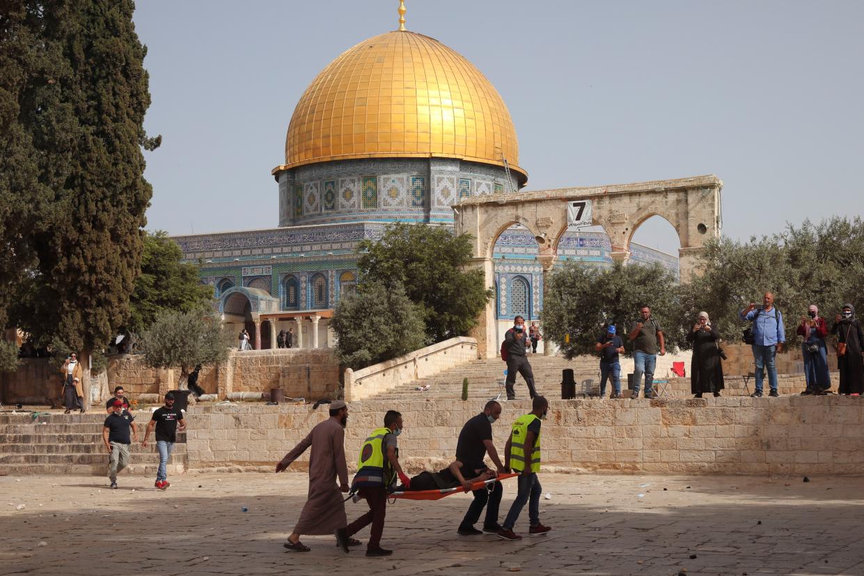 Palestinians evacuate a wounded man during clashes with Israeli security forces in front of the Dome of the Rock Mosque at the Al Aqsa Mosque compound in Jerusalem's Old City on Monday, May 10, 2021.