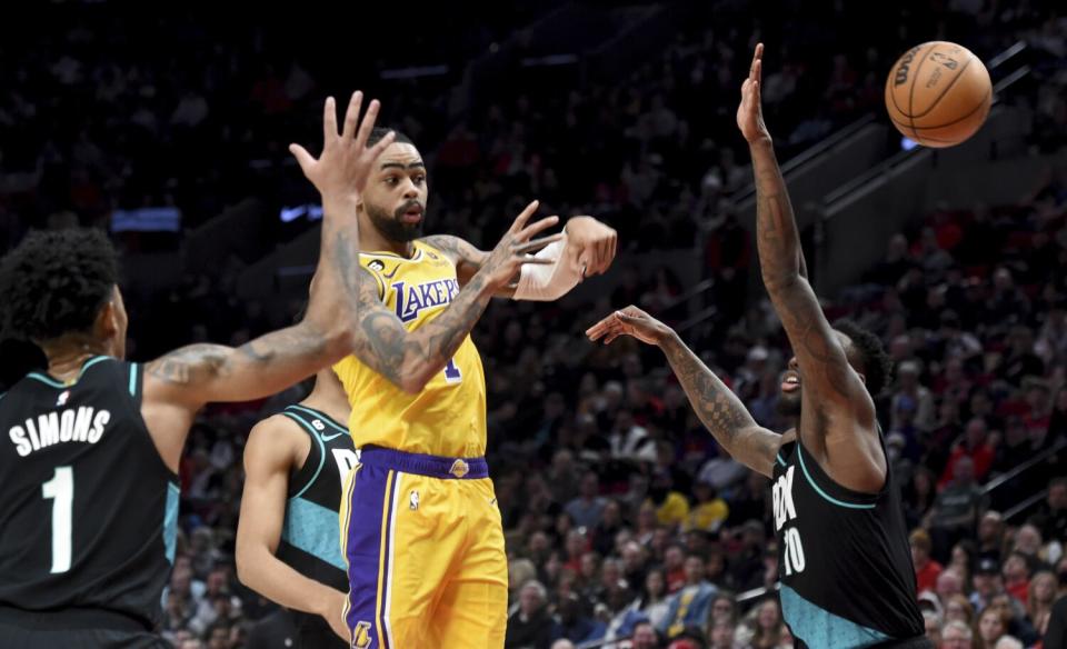 Lakers guard D'Angelo Russell, center, passes as Trail Blazers Anfernee Simons, left, and Nassir Little defend.