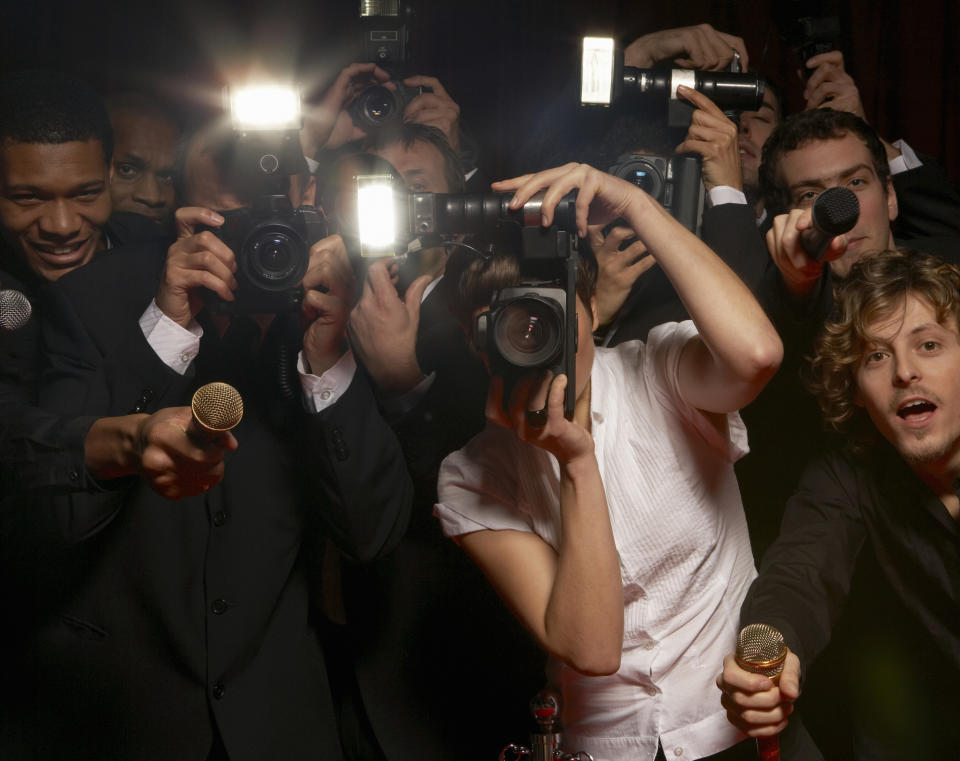 Paparazzi with cameras taking photos at an event, possibly indicating celebrity presence or an important social function related to fame and wealth