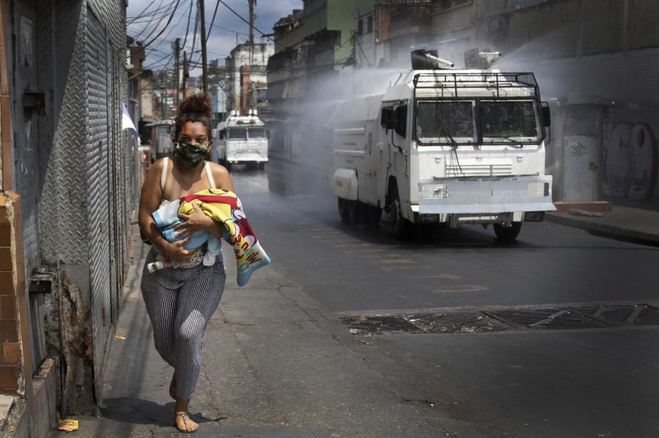 A woman with a baby runs from a truck spraying disinfectant in Venezuela.