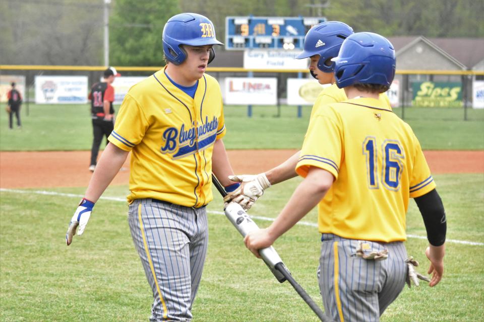 Dawson Glassco celebrates with teammates Kody Earl (16) and AJ Sarver after the duo scored on a Ben Seitzinger double against Orleans.