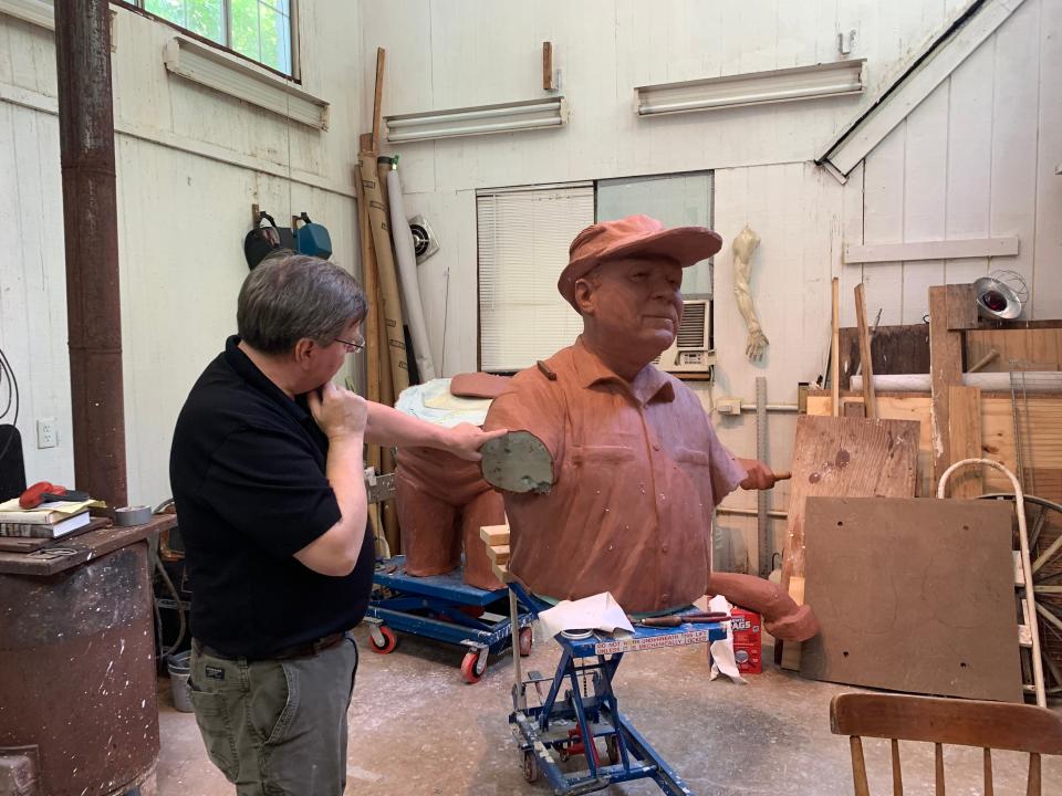 Toby Mendez points to a mold of Lefty Kreh in his studio.