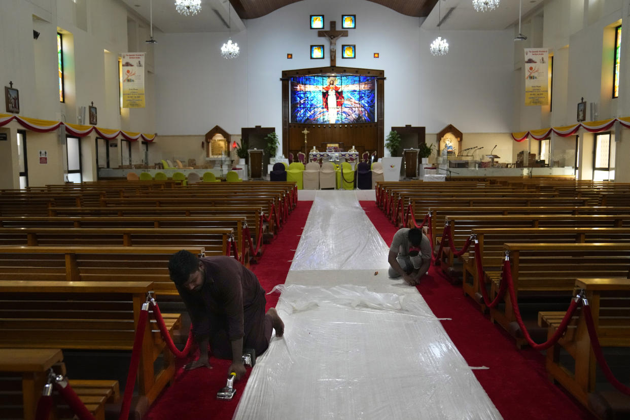 Workers adjust a red carpet, at Sacred Heart church in preparation of a papal visit, in Manama, Bahrain, Wednesday, Nov. 2, 2022. Pope Francis is making the November 3-6 visit to participate in a government-sponsored conference on East-West dialogue and to minister to Bahrain's tiny Catholic community, part of his effort to pursue dialogue with the Muslim world. (AP Photo/Hussein Malla)