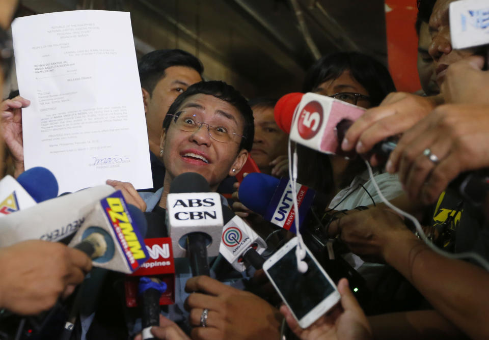 Maria Ressa, left, the award-winning head of a Philippine online news site Rappler that has aggressively covered President Rodrigo Duterte's policies, shows her release order after posting bail at a Regional Trial Court following an overnight arrest by National Bureau of Investigation agents on a libel case Thursday, Feb. 14, 2019 in Manila, Philippines. Ressa, who was selected by Time magazine as one of its Persons of the Year last year, was arrested over a libel complaint from a businessman which Amnesty International has condemned as "brazenly politically motivated." Duterte's government says the arrest was a normal step in response to the complaint. (AP Photo/Bullit Marquez)