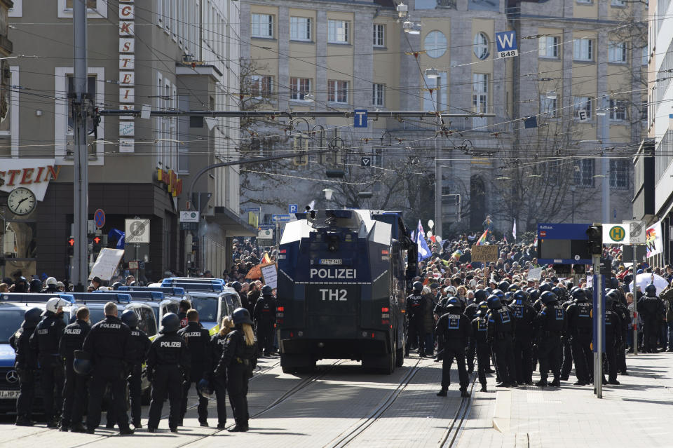 Police forces stand next to a water canon during a rally under the motto "Free citizens Kassel - basic rights and democracy" i Kassel, Germany, Saturday, March 20, 2021. According to police, several thousand people were on the move in the city center and disregarded the instructions of the authorities during the unregistered demonstration against Corona measures. (Swen Pfoertner/dpa via AP)