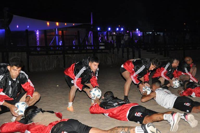 Una imagen inusual: Deportivo Riestra y su entrenamiento en la playa, a las 3 AM; detrás, las luces de una discoteca