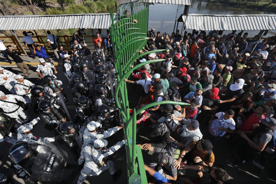 Migrants charge on the Mexican National Guardsmen at the border crossing between Guatemala and Mexico in Tecun Uman, Guatemala, Saturday, Jan. 18, 2020. More than a thousand Central American migrants surged onto the bridge spanning the Suchiate River, that marks the border between both countries, as Mexican security forces attempted to impede their journey north. (AP Photo/Marco Ugarte)