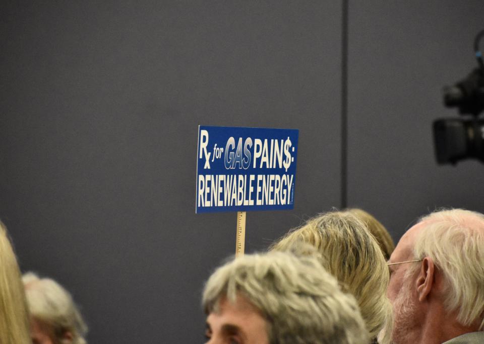 Margaret Stewart holds up a sign advocating for renewable energy over gas at a public comment session on LG&E and KU's future energy generation. Stewart, an LG&E customer, said she disapproved of the utility's plans for additional natural gas for their climate and environmental health impacts. Aug. 16, 2023