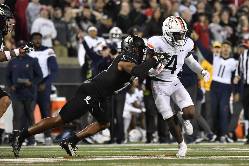 Louisville defensive back Devin Neal, left, attempts to tackle Virginia wide receiver Malik Washington (4) during the second half of an NCAA college football game in Louisville, Ky., Thursday, Nov. 9, 2023. (AP Photo/Timothy D. Easley)