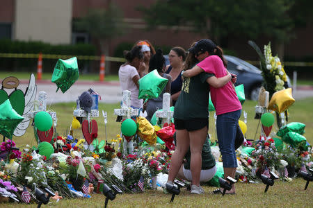 People mourn at a makeshift memorial left in memory of the victims killed in a shooting at Santa Fe High School in Santa Fe, Texas, U.S., May 23, 2018. REUTERS/Loren Elliott