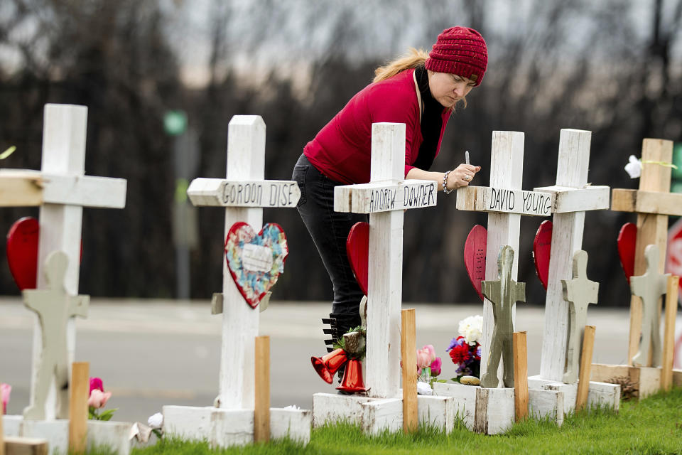 In this Feb. 8, 2019, photo, Tabatha Miller visits a memorial for Camp Fire victims in Paradise, Calif. Miller is helping rescue and re-settle animals displaced during the November 2018 blaze. In the 100 days since a wildfire nearly burned the town of Paradise off the map, the long recovery is just starting. Work crews have been cutting down trees and clearing burned-out lots, but Paradise is mostly a ghost town where survivors still dig for keepsakes in the foundations of their homes. (AP Photo/Noah Berger)