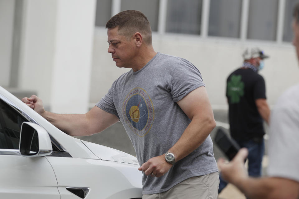 NASA astronaut Robert Behnken places a sticker on a Tesla X SUV as he walks outside the Neil A. Armstrong Operations and Checkout Building, at the Kennedy Space Center in Cape Canaveral, Fla., Wednesday, May 27, 2020. The two astronauts will fly on a SpaceX test flight to the International Space Station. For the first time in nearly a decade, astronauts will blast into orbit aboard an American rocket from American soil, a first for a private company. (AP Photo/John Raoux)