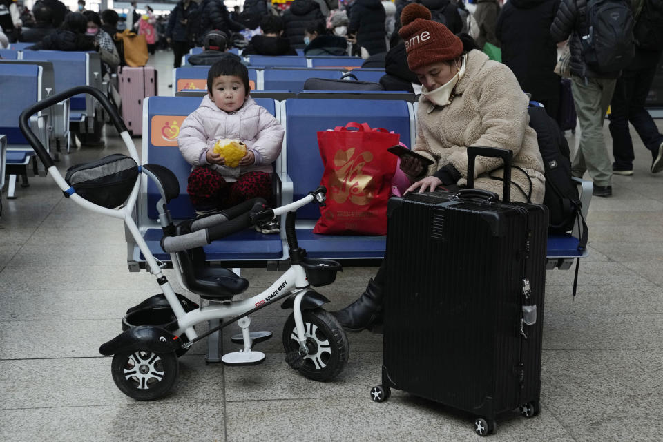 A child eats bread while waiting for a train at the South Train Station in Beijing, China, Friday, Jan. 14, 2022. The number of babies born in China continued to shrink last year in a decade-long trend, official data showed Monday, as a declining workforce adds pressure to the ruling Communist Party's ambitions to boost national wealth and global influence. (AP Photo/Ng Han Guan)