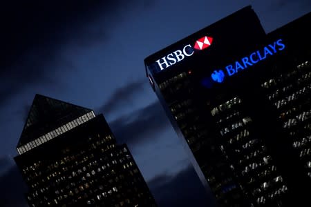 HSBC and Barclay's buildings are lit up at dusk in the Canary Wharf financial district of London