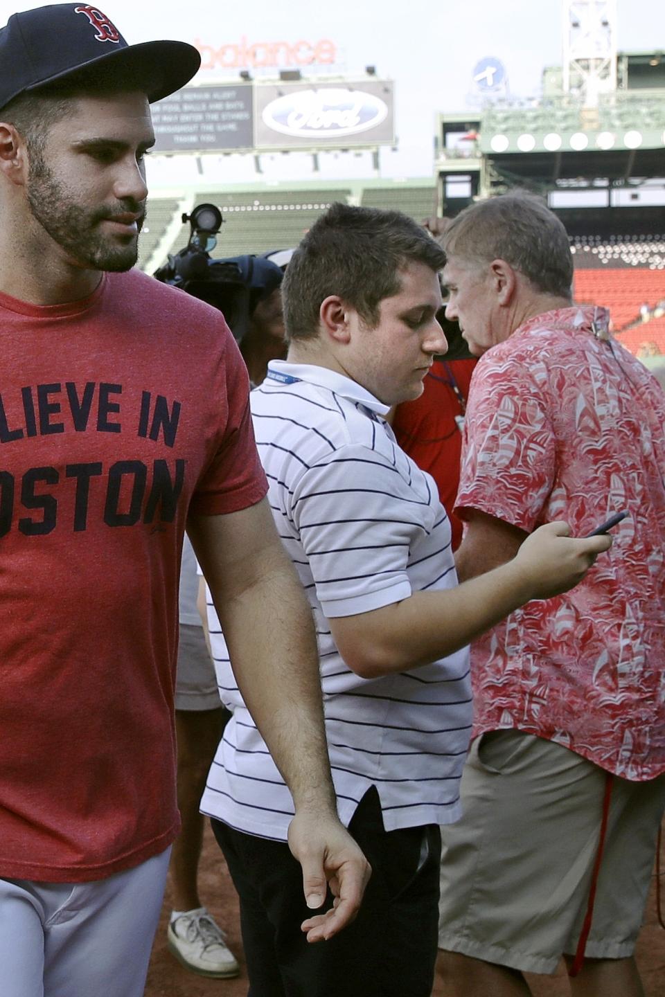 FILE - In this Aug. 28, 2018, file photo, Boston Red Sox's J.D. Martinez walks past Chris Cotillo, center, Red Sox beat writer for MassLive.com, prior to a baseball game at Fenway Park in Boston. Cotillo raised tens of thousands of dollars in 2020 by selling autographed baseball memorabilia he had collected as a teen and that others donated for the auction. (AP Photo/Charles Krupa, File)