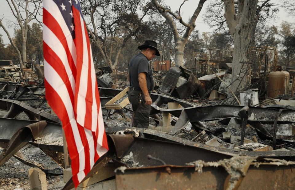 Ed Bledsoe searches through what remains of his home, Monday, Aug. 13, 2018, in Redding, Calif. Bledsoe's wife, Melody, great-grandson James Roberts and great-granddaughter Emily Roberts were killed at the home in the Carr Fire. (AP Photo/John Locher)