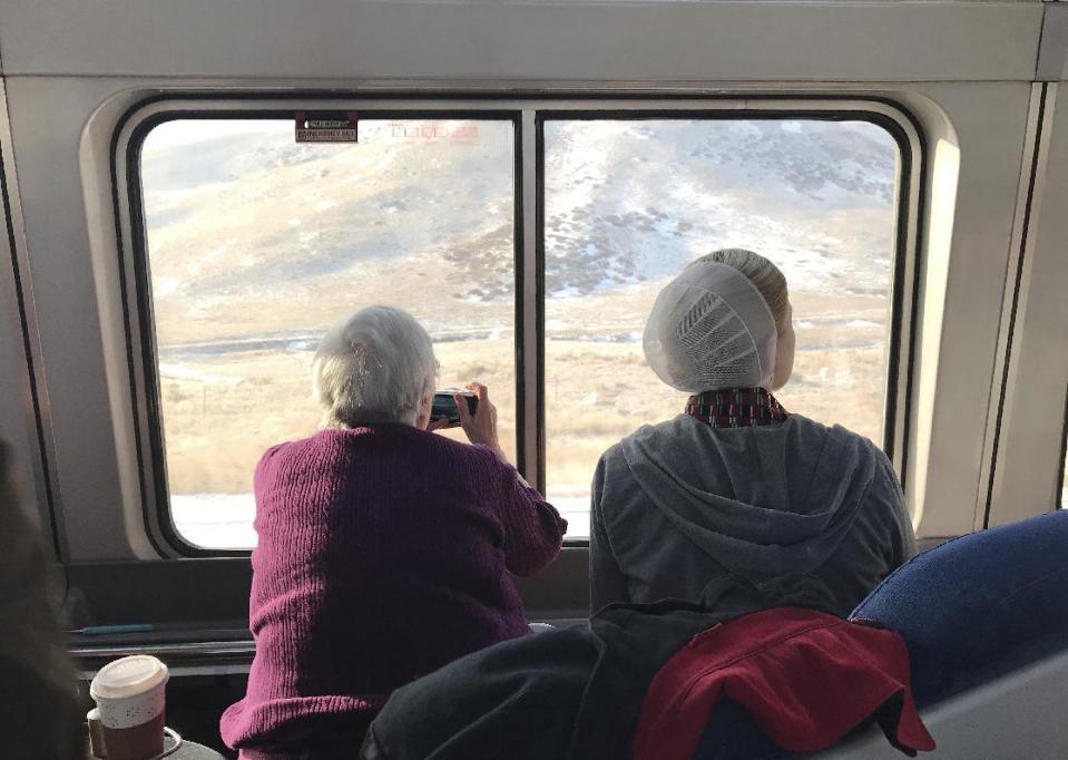 In this photo taken on on Jan. 26, 2017, two women take photos of the Sierra Nevada mountains on the California Zephyr train. AP Tampa correspondent Tamara Lush spent 15 days traveling via train across the U.S. as part of Amtrak's residency program, designed for creative professionals to spend time writing on the rails. She spoke with dozens of people _ fellow travelers, friends and family waiting for loved one at stations, train workers _ and filed occasional dispatches for the Tales on a Train project. (AP Photo/Tamara Lush)
