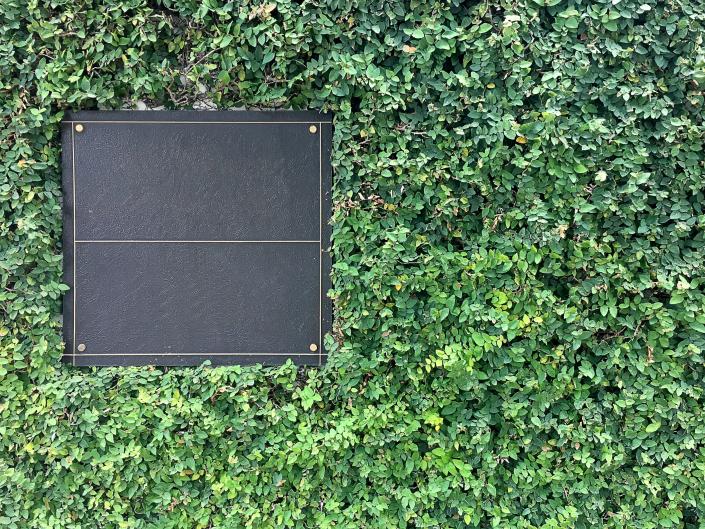 A boxwood wall with a bulletin board in it