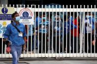 Workers wait in line to leave a Top Glove factory after their shifts in Klang