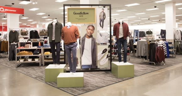 An in-store display of men's clothing at Target. The new exclusive brand is called Goodfellow and Co, and the display has three mannequins with a sweater, jacket, and T-shirt, each paired with a different pair of pants.