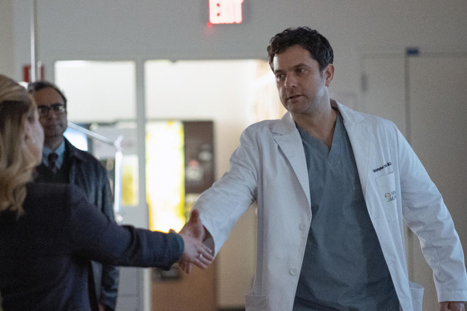 Joshua Jackson shakes hands in a doctor's coat