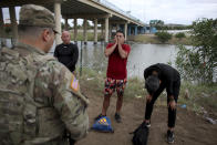 Three migrants from Cuba stand in front of a National Guardsman after crossing the Rio Grande river in Eagle Pass, Texas, Sunday May 22, 2022. Little has changed in what has quickly become one of the busiest corridors for illegal border crossings since a federal judge blocked pandemic-related limits on seeking asylum from ending Monday. (AP Photo/Dario Lopez-Mills)