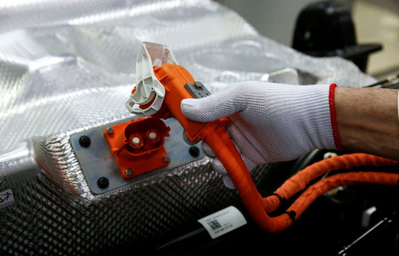 FILE PHOTO: Worker connects the battery during the assembly of a VW e-Golf electric car at the Transparent Factory in Dresden