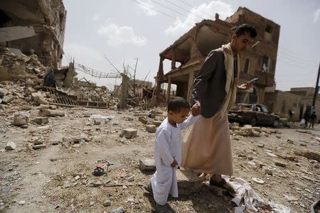 A man and a boy walk at a site hit by a Saudi-led air strike in Yemen's capital Sanaa July 3, 2015.REUTERS/Khaled Abdullah