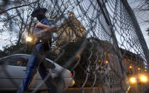 A Washington State Patrol trooper walks past new security fencing installed on Friday, Jan. 8, 2021, around the state Capitol in Olympia, Wash.. in anticipation of the legislative session opening on Monday. (Tony Overman/The Olympian via AP)