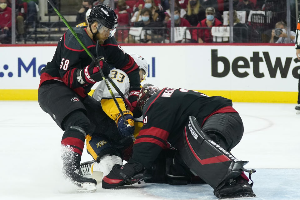 Carolina Hurricanes defenseman Jani Hakanpaa (58) and goaltender Alex Nedeljkovic (39) defend the goal against Nashville Predators right wing Viktor Arvidsson (33) during the first period in Game 1 of an NHL hockey Stanley Cup first-round playoff series in Raleigh, N.C., Monday, May 17, 2021. (AP Photo/Gerry Broome)