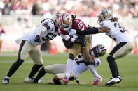 San Francisco 49ers wide receiver Brandon Aiyuk (11) runs against New Orleans Saints linebacker Demario Davis, left, cornerback Alontae Taylor, bottom, and safety Tyrann Mathieu during the first half of an NFL football game in Santa Clara, Calif., Sunday, Nov. 27, 2022. (AP Photo/Godofredo A. Vásquez)