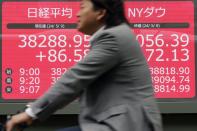 A person rides bicycle past an electronic stock board showing Japan's Nikkei 225 and New York Dow indexes at a securities firm Thursday, May 9, 2024, in Tokyo. (AP Photo/Eugene Hoshiko)